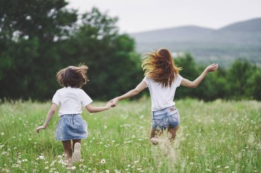 Genç anne ve kızı papatya tarlasında eğleniyorlar.