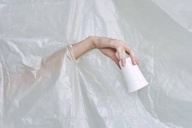 Plastik ve polietilen yırtıklar olan bir kadın eli.