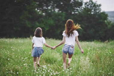 Genç anne ve kızı papatya tarlasında eğleniyorlar.