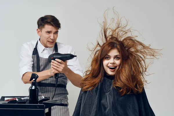 man hairdresser making hairstyle to  client in salon