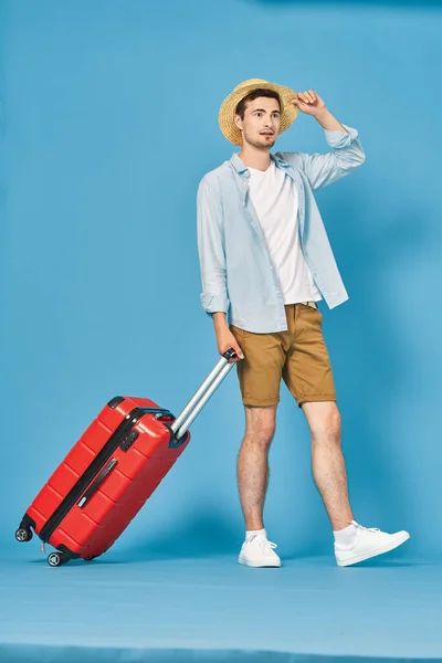 スタジオショットの若い男の観光客引っ張っ赤スーツケース — ストック写真