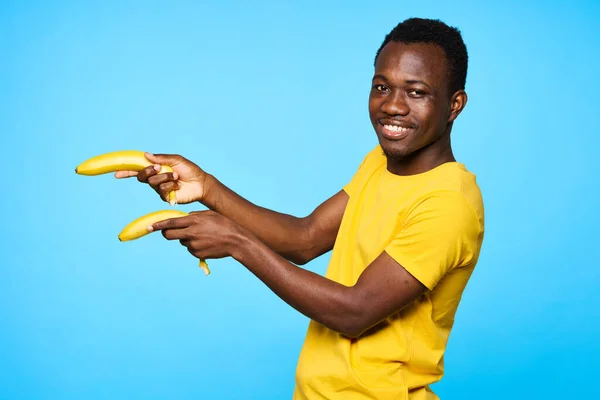 Young african man pointing with bananas   isolated on blue background
