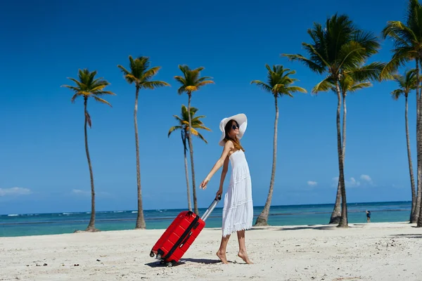 熱帯のビーチにスーツケースを着た若い美しい女性 — ストック写真