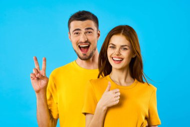 Stüdyoda mavi arka planda genç ve yakışıklı bir erkek ve kadın var. 