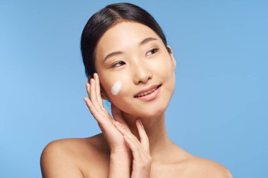Genç Asyalı kadın krem sürüyor. 
