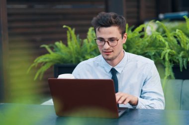 Kafede dizüstü bilgisayarla çalışan genç adam. 