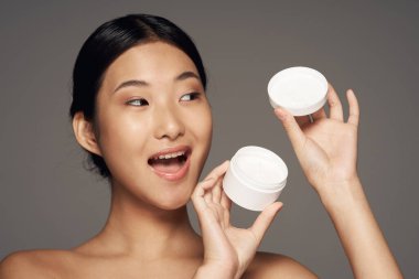 Genç ve güzel Asyalı bir kadın krem tutuyor. 