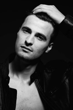 Siyah ve beyaz. Genç ve yakışıklı bir adam karanlık arka planda kameraya bakıyor. Stüdyo çekimi  