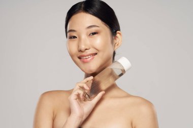 Arkaplanda losyon tutan güzel Asyalı kadın portresi. 