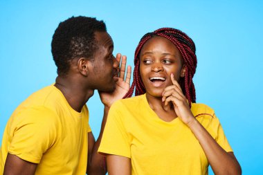 Afrika görünümlü erkek ve kadın izole edilmiş arka planda bir sırrı paylaşıyorlar.