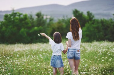 Genç anne ve kızı papatya tarlasında eğleniyorlar.