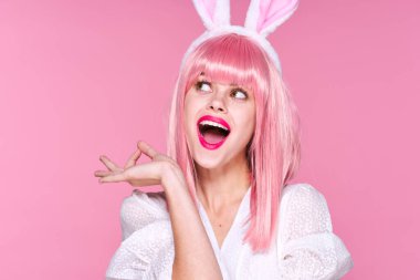 Pembe peruklu ve tavşan kulaklı güzel bir kadının pembe arka planda bakışları.