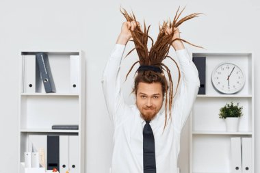 Ofiste oturan genç işadamı saç topluyor. 