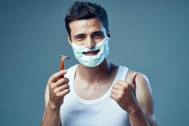 Stüdyo çekimi. Genç yakışıklı adam tıraş oluyor ve baş parmağını gösteriyor. 