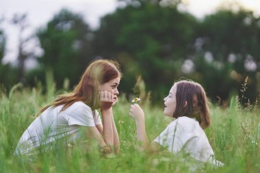 Genç anne ve kızı papatya tarlasında eğleniyorlar.