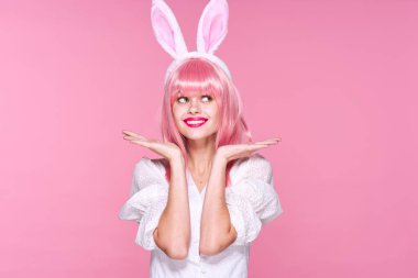 Pembe peruklu güzel bir kadının pembe arka planda tavşan kulağı taktığı sahneler.