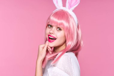 Pembe peruklu genç kadın ve pembe arka planda tavşan kulaklı stüdyo.