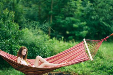 Genç ve güzel bir kadın hamakta dinleniyor. 