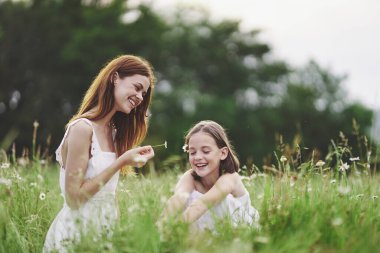 Genç anne ve kızı papatya tarlasında eğleniyorlar.