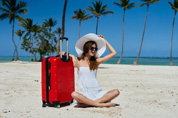 young beautiful woman with suitcase on tropical beach