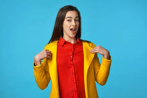 young beautiful woman in yellow jacket is surprised   in Studio with blue Background.