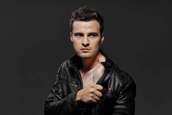 Portrait of young  man in leather jacket  on dark background. Studio shot.