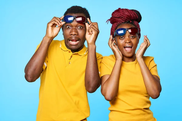 confused  couple in 3D glasses in studio on blue background