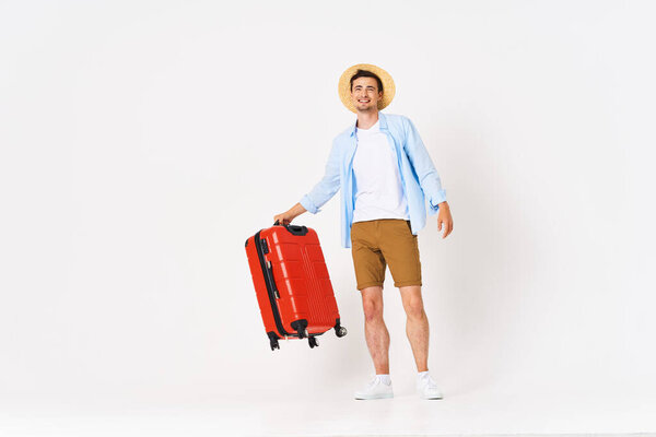 Studio shot of young happy  man tourist with red suitcase