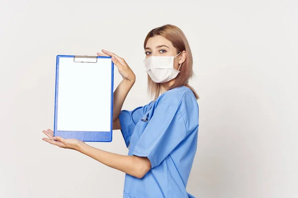 工作室拍摄 戴口罩的年轻护士在白色背景上展示剪贴板 — 图库照片