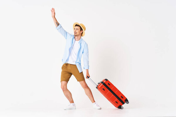 Studio shot of young man tourist pulling suitcase