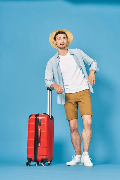 Studioaufnahme Eines Jungen Mannes Mit Gepäck Auf Blauem Grund — Stockfoto