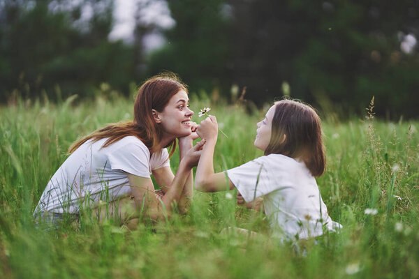 Young mother and her daughter having fun on camomile field