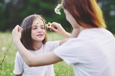 Genç anne ve kızı papatya tarlasında eğleniyorlar.