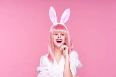 Pembe peruklu ve pembe arka planda poz veren tavşan kulaklı güzel bir kadının sudio çekimi.