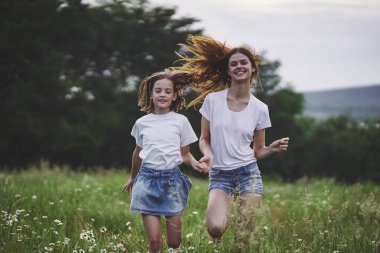 Genç anne ve kızı papatya tarlasında eğleniyorlar.