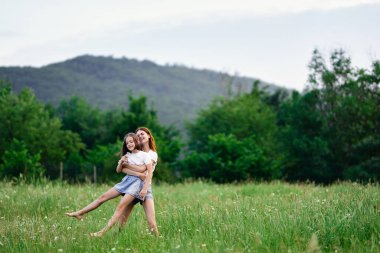 Genç anne ve kızı papatya tarlasında eğleniyorlar.
