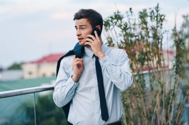 Terasta telefonu olan yakışıklı bir iş adamı. 