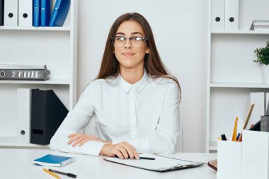 Genç ve güzel bir iş kadını ofiste masa başında oturuyor.