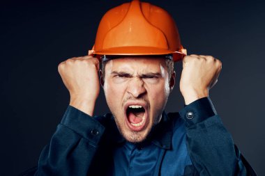 Stüdyo çekimi. Turuncu kasklı endüstriyel kızgın işçi bağırıyor. 