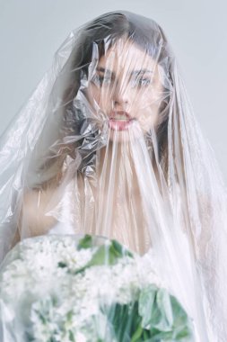 Plastiğin altında çiçekleri olan güzel bir kadın