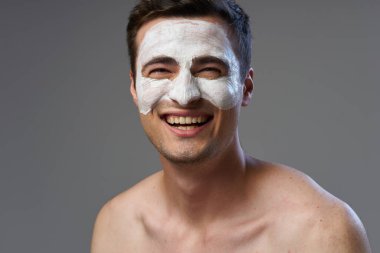 Stüdyoda gülümseyen yüz maskeli genç yakışıklı adam. 