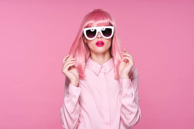 Pembe peruklu ve güneş gözlüklü kadın stüdyoda pembe arka planda 