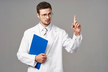 Stüdyo çekimi. Genç doktor izole edilmiş bir geçmişi işaret ediyor. 