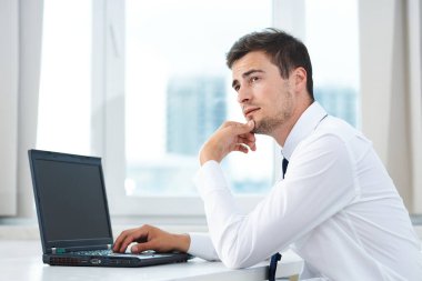 Laptop düşünen genç yakışıklı iş adamı. 