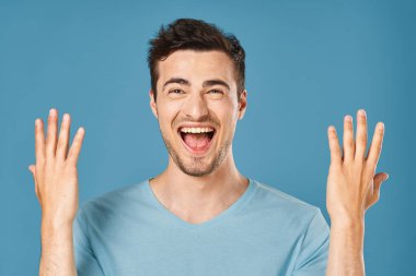 Genç yakışıklı adam mavi arka planda stüdyoda mutlu. 