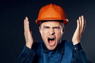 Stüdyo çekimi. Turuncu kasklı sanayi işçisi ağlıyor 