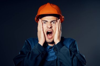 Stüdyo çekimi. Turuncu kasklı sanayi işçisi korkuyor. 