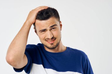 Genç, yakışıklı, kafası karışmış, beyaz arka planda yalnız bir adam. 