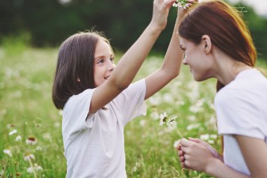 Genç anne ve kızı papatya tarlasında eğleniyorlar.