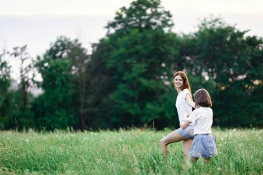 Genç anne ve kızı papatya tarlasında eğleniyorlar.